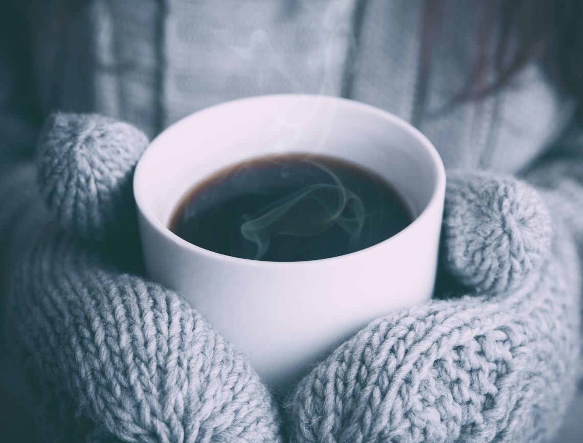 Holding hot coffee wearing mittens
